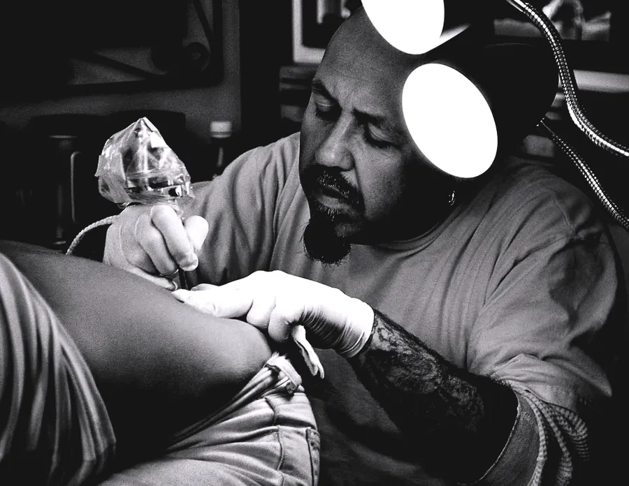 Tatuator lucrând la lumină într-un salon